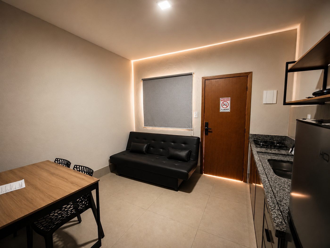 Sala com sofá, mesa de refeições e cozinha integrada